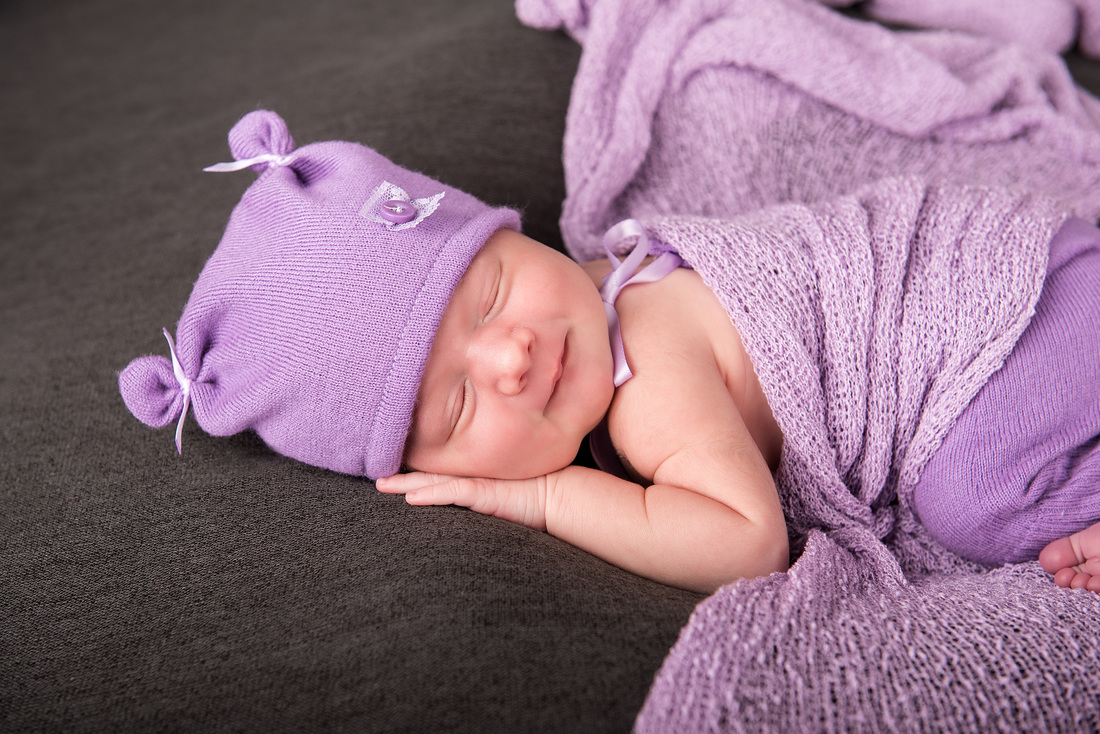 Newborn baby girl in purple smiling